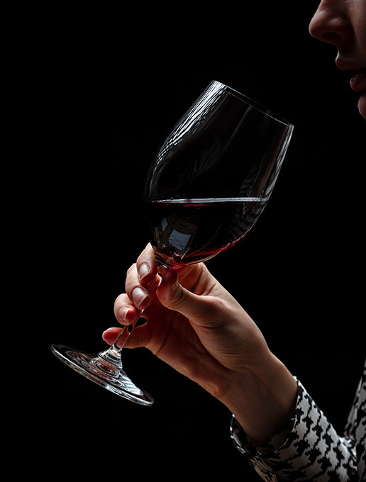 Une jeune femme savourant un verre de vin dans une ambiance feutrée pour célébrer Noël au restaurant Dans le Noir ?