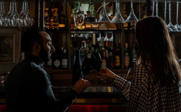 Deux personnes partageant un moment autour d’un verre dans une ambiance intimiste, évoquant une expérience de rencontre et de table partagée